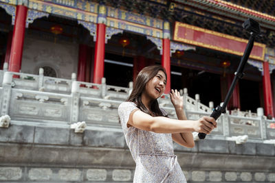 Smiling women vlogging while standing against temple