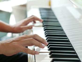 Cropped hands of man playing piano