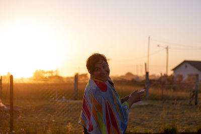 Portrait of woman standing on field against sky during sunset