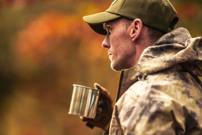 Young man drinking coffee while standing outdoors