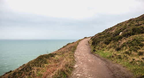 Road amidst sea against sky