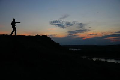 Silhouette woman standing against sky during sunset