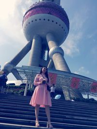 Low angle view of woman standing against cloudy sky