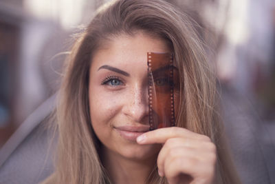 Close-up portrait of beautiful young woman with camera film