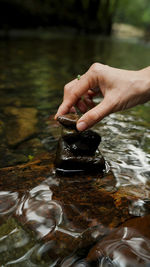 Hand stacking rock beside stream