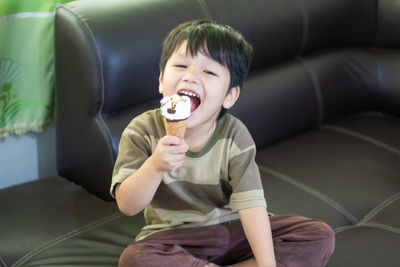 Portrait of boy eating ice cream on sofa