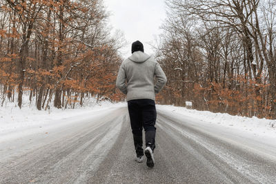 Rear view of man walking on road during winter