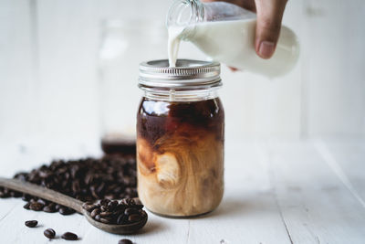 Cropped hand pouring milk in jar