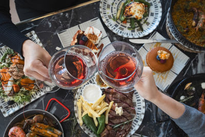 Overhead view of two women making a celebratory toast with wine glasses