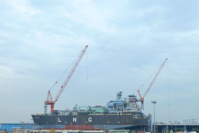 Low angle view of cranes at harbor against sky