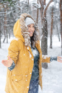 Portrait of smiling woman with snow covered tree during winter