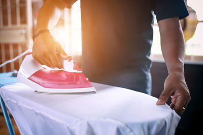 Midsection of man ironing shirt at home