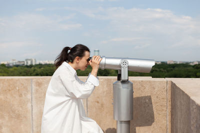 Rear view of woman photographing against sky