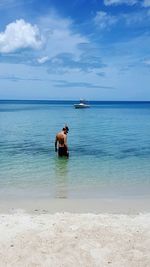 Rear view of man standing in sea against sky