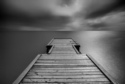 Wooden pier over sea against sky