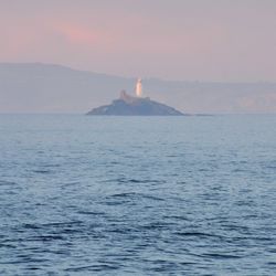 Scenic view of sea against sky during sunset with lighthouse in centre 