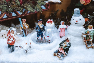 Christmas figures of snowman and children playing in the snowy street. festive winter toys, new year