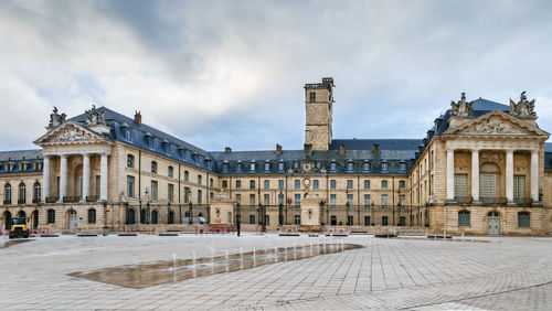 Buildings in town against cloudy sky