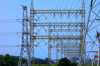 Low angle view of electricity pylon against blue sky