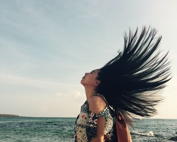 Beautiful woman standing by sea against sky