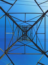 Low angle view of electricity pylon against blue sky