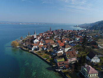 High angle view of townscape by sea against sky