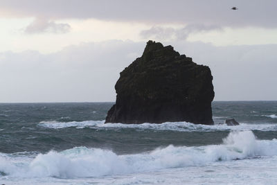 Scenic view of sea by cliff against sky