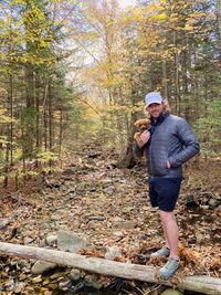 Full length of man standing in forest with a puppy