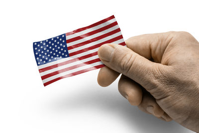 Cropped hand holding american flag against white background