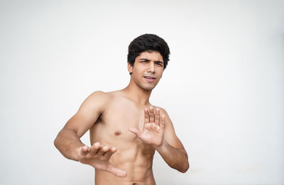 Portrait of young man standing against white background