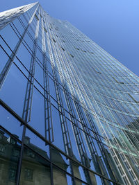 Low angle view of glass building against clear sky