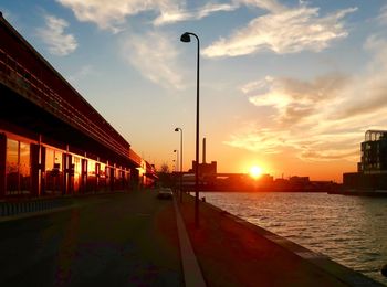 Street by city against sky during sunset