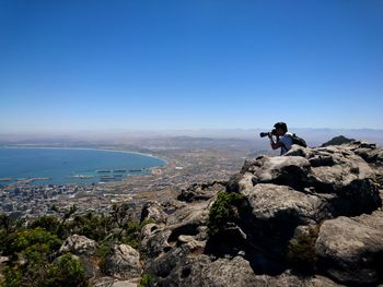 Man on rocks against clear blue sky