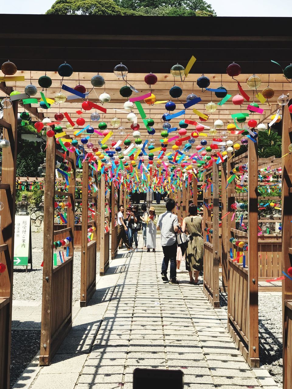 REAR VIEW OF PEOPLE WALKING ON STREET MARKET