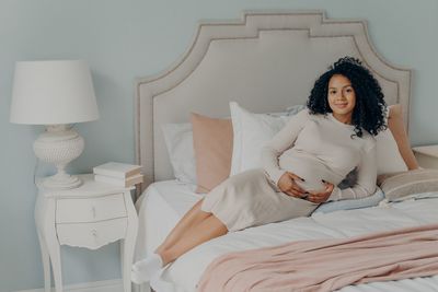 Young woman sitting on bed at home