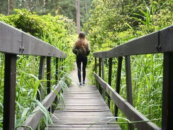 Rear view of woman walking on footbridge