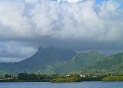 Idyllic shot of sea and mountains against cloudy sky