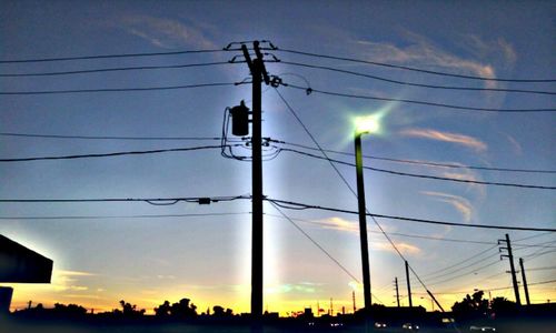 Low angle view of electricity pylon against cloudy sky