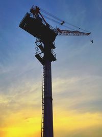 Low angle view of silhouette crane against sky during sunset