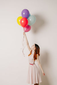 Woman holding balloons against white background