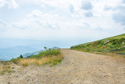 Road leading towards mountains against sky