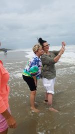 Young couple kissing on beach against sky