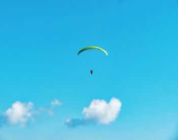 Low angle view of person paragliding against blue sky