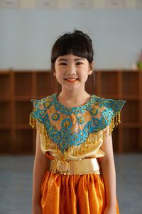 Portrait of smiling girl standing against wall