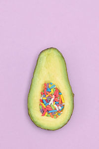 Slice of avocado cut in half and sprinkles candy