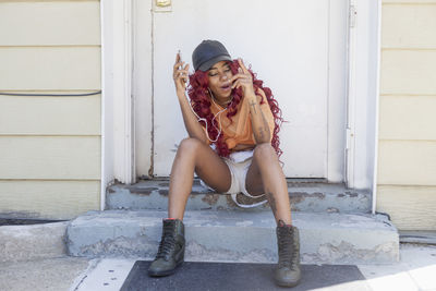 Young woman listening to music at her front door