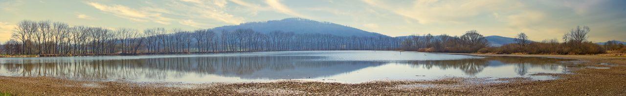 Panoramic view of lake by trees against sky