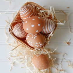 Directly above shot of easter eggs with shavings in basket