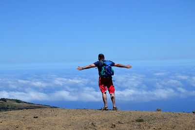 Man with arms outstretched on hillside