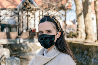 Beautiful young woman wearing black face mask, looking at camera. epidemic, covid, corona virus.